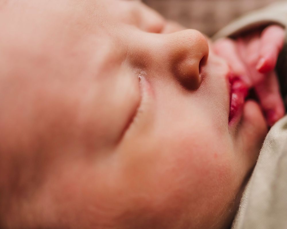 Close-up profile view of a sleeping newborn baby's face showing peaceful expression.