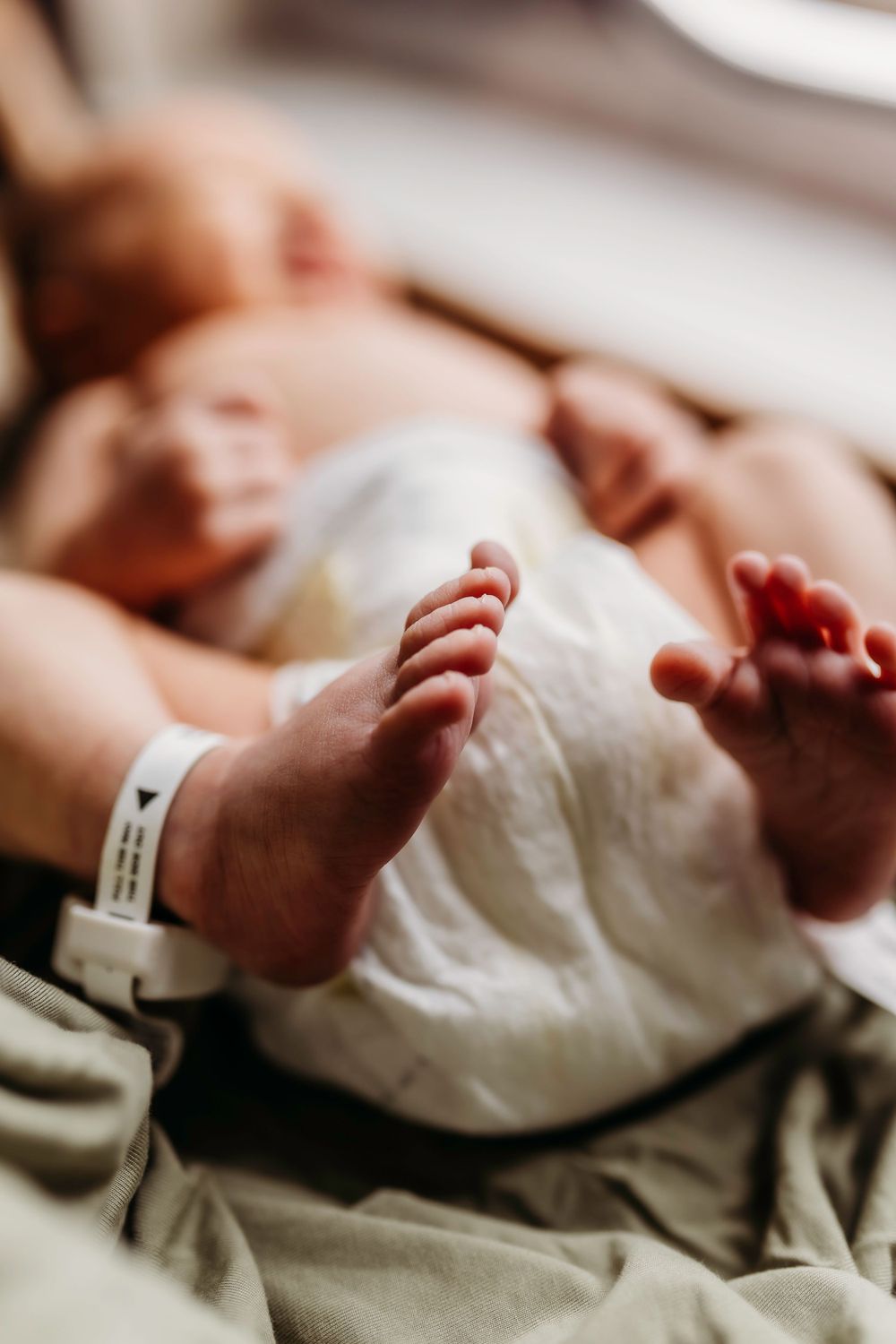 Close-up of newborn baby's tiny feet with hospital identification bracelet.