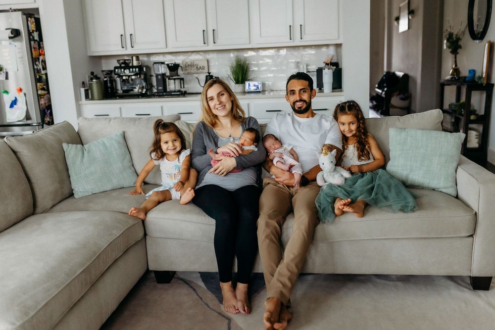 Happy family relaxing together on a gray sectional sofa in their modern white kitchen.