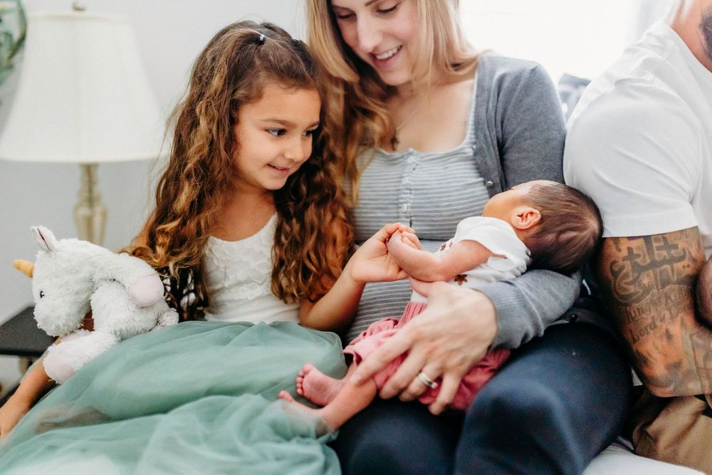 An intimate family moment as they bond with their newborn baby on a cozy couch.