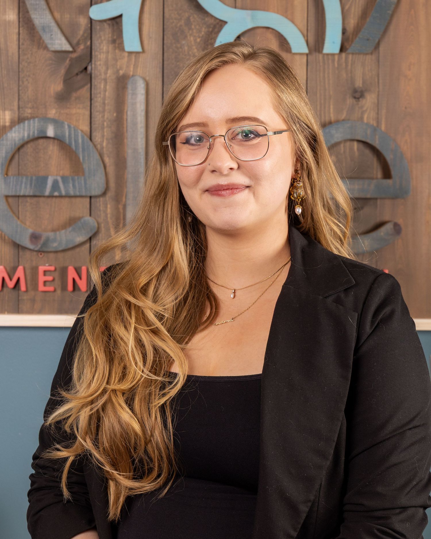 Professional headshots against a wooden wall background with blue text signage.