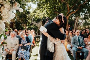 Wedding guests toss white confetti and celebrate during an outdoor garden ceremony.