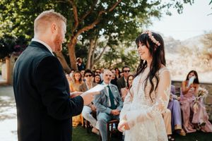 Couple sharing a romantic moment during their outdoor wedding ceremony with guests watching in the background.