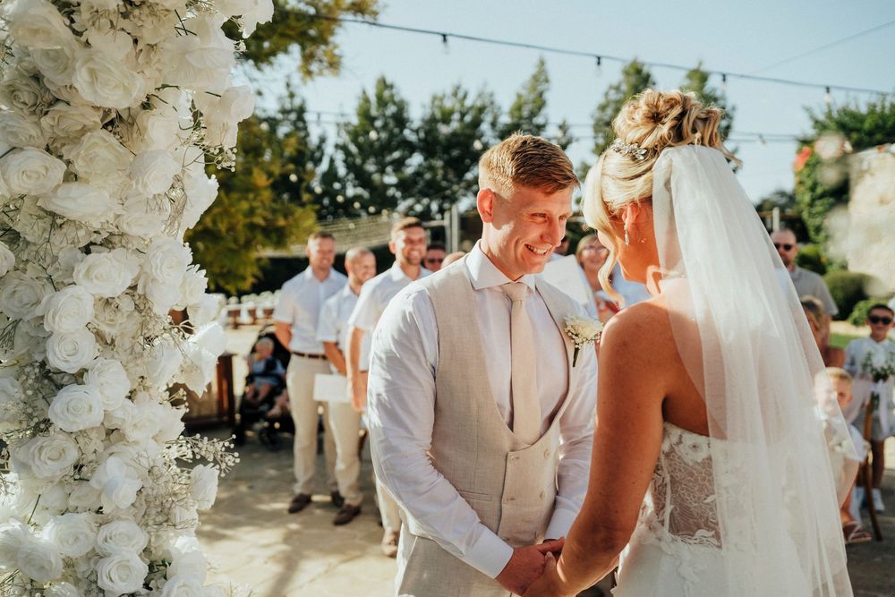 A joyful outdoor wedding ceremony with guests seated under trees and string lights.