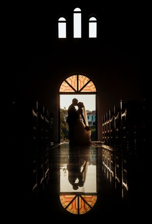 A silhouetted figure stands in a dramatic backlit doorway creating a moody architectural composition.