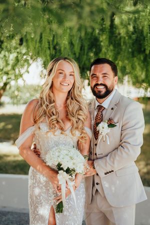 A happy couple shares joyful moments together in a sunny outdoor setting during their wedding celebration.