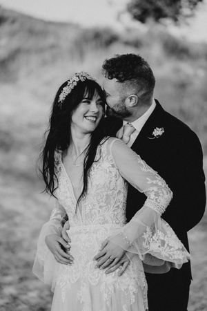 A romantic black and white wedding photo series showing a couple embracing and laughing together in an outdoor setting.