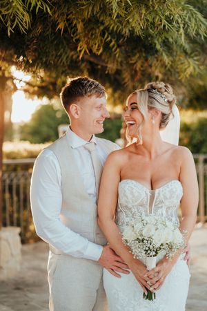 A romantic wedding couple shares intimate moments in a series of sunset photos with baby's breath bouquet.