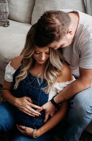 Intimate couple in denim and white share tender moments on a couch in a romantic photoshoot sequence.