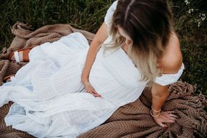 A romantic couple in white and brown clothing embraces on a rustic wooden surface outdoors.