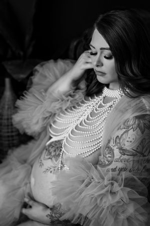 Black and white boudoir photo featuring pearl necklaces and sheer fabric with delicate floral details.