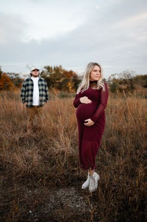 A couple poses in a rustic autumn field during golden hour for a romantic outdoor photoshoot.