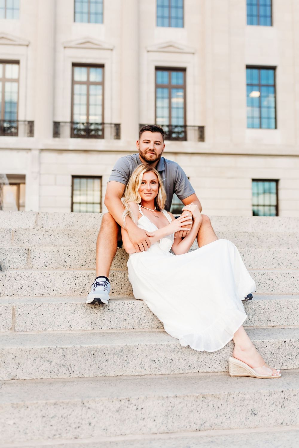 Couple sitting on stone steps of classical building.