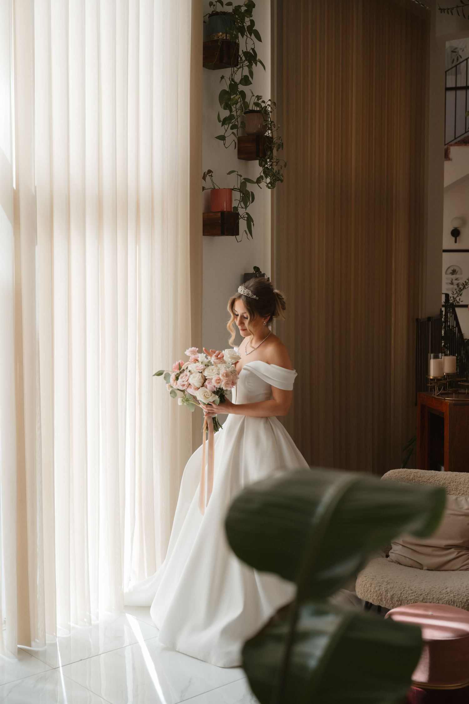 Bride in elegant white dress holding romantic bouquet of white flowers and greenery.