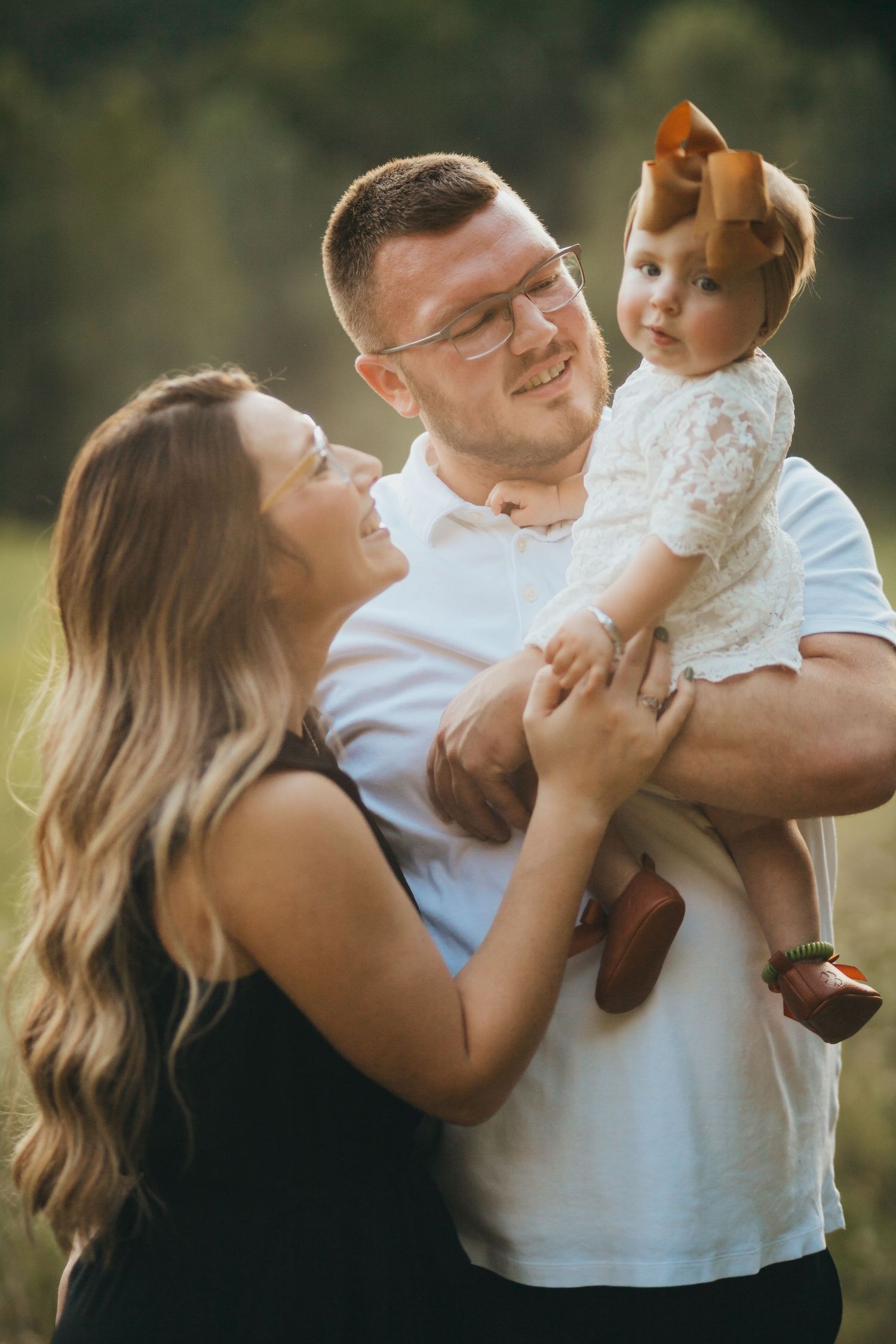 Family of three sharing joyful moment together outdoors in natural lighting.