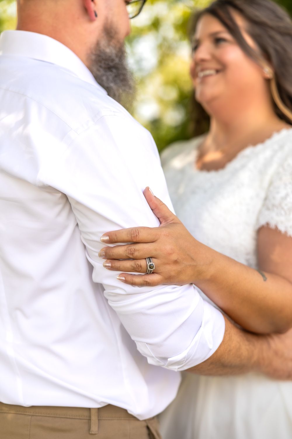 A couple in white clothing share an intimate dance moment outdoors with natural lighting and soft focus.