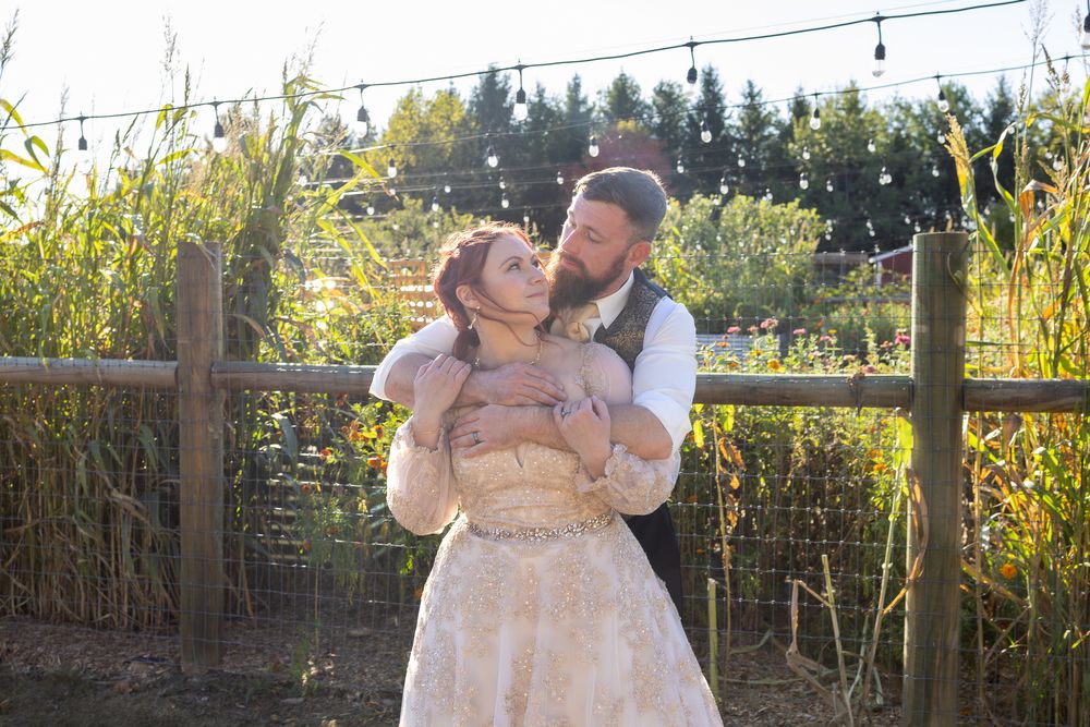 A couple dances together in an outdoor garden setting with string lights overhead during a romantic celebration.