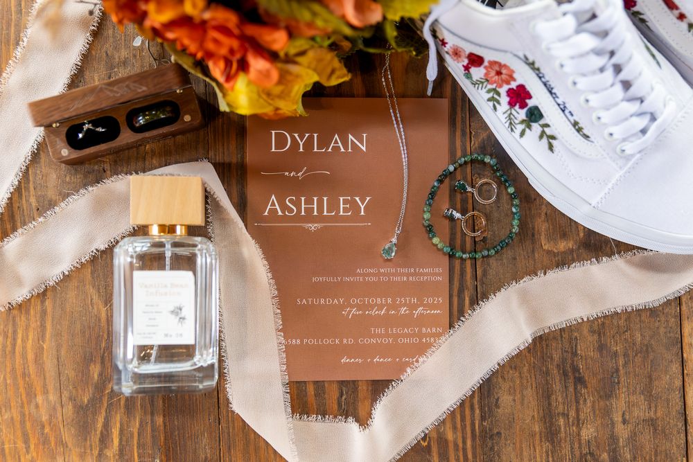 Rustic wedding invitation suite with copper-toned text on wood background with white decorative elements and envelopes.
