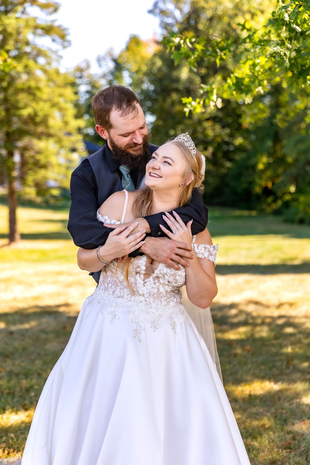 A joyful couple shares a candid moment together outdoors on their wedding day in a sunlit garden setting.