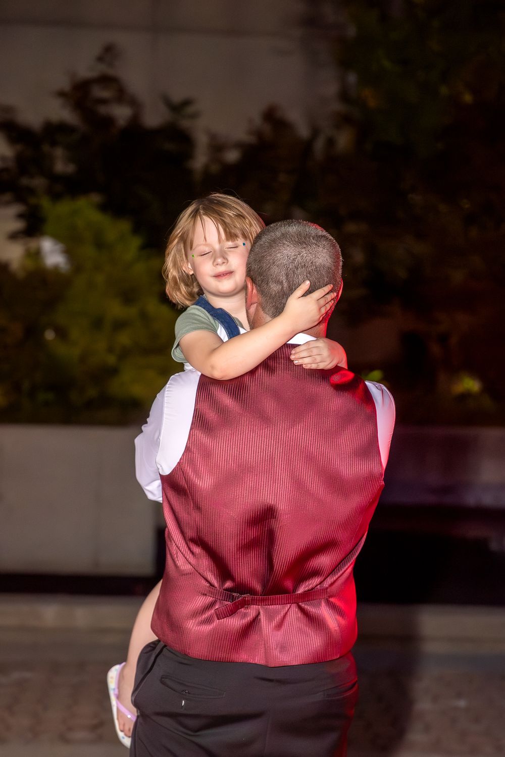 Sweet candid moment of a child hugging an adult during a wedding reception dance.