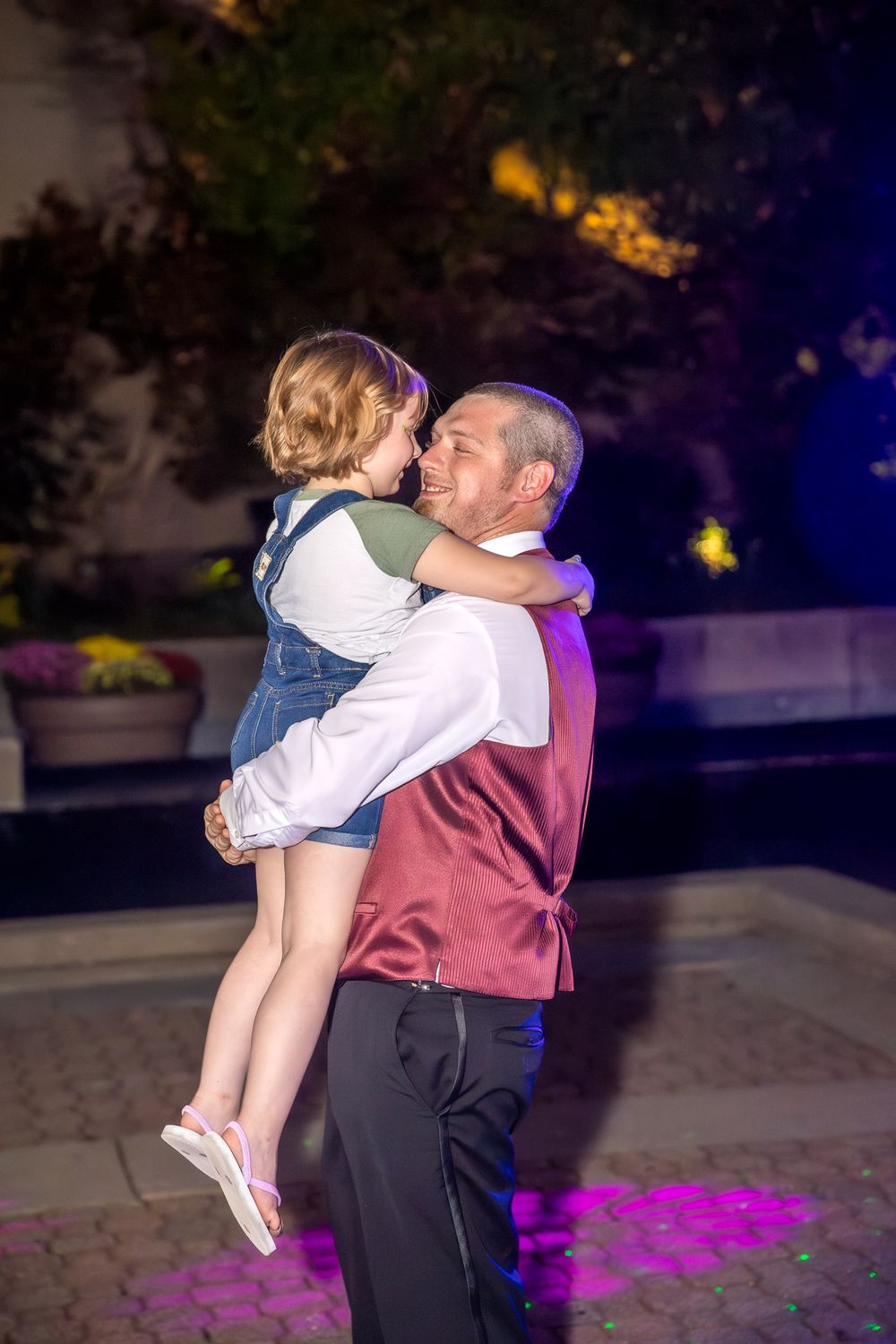 A tender dance moment captured between a father and young child during an evening wedding reception.