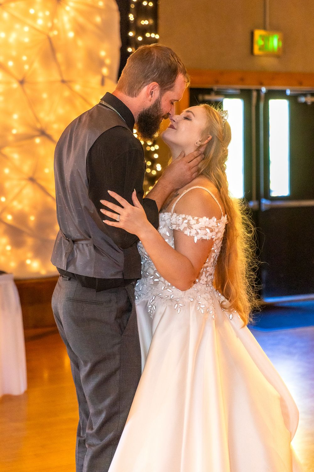 A romantic first dance between newlyweds at their wedding reception with warm glowing lights in the background.