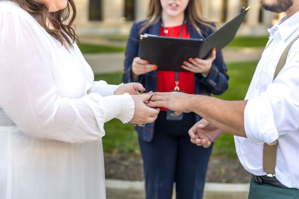 Close-up of hands exchanging rings during outdoor wedding ceremony.