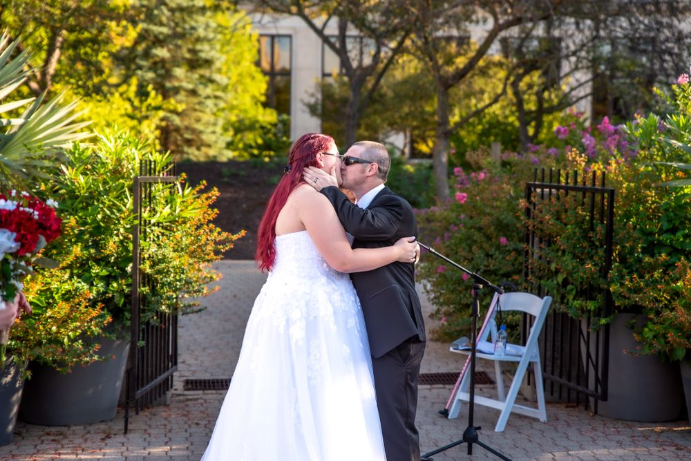 A wedding couple shares a tender moment in a garden setting surrounded by lush greenery.