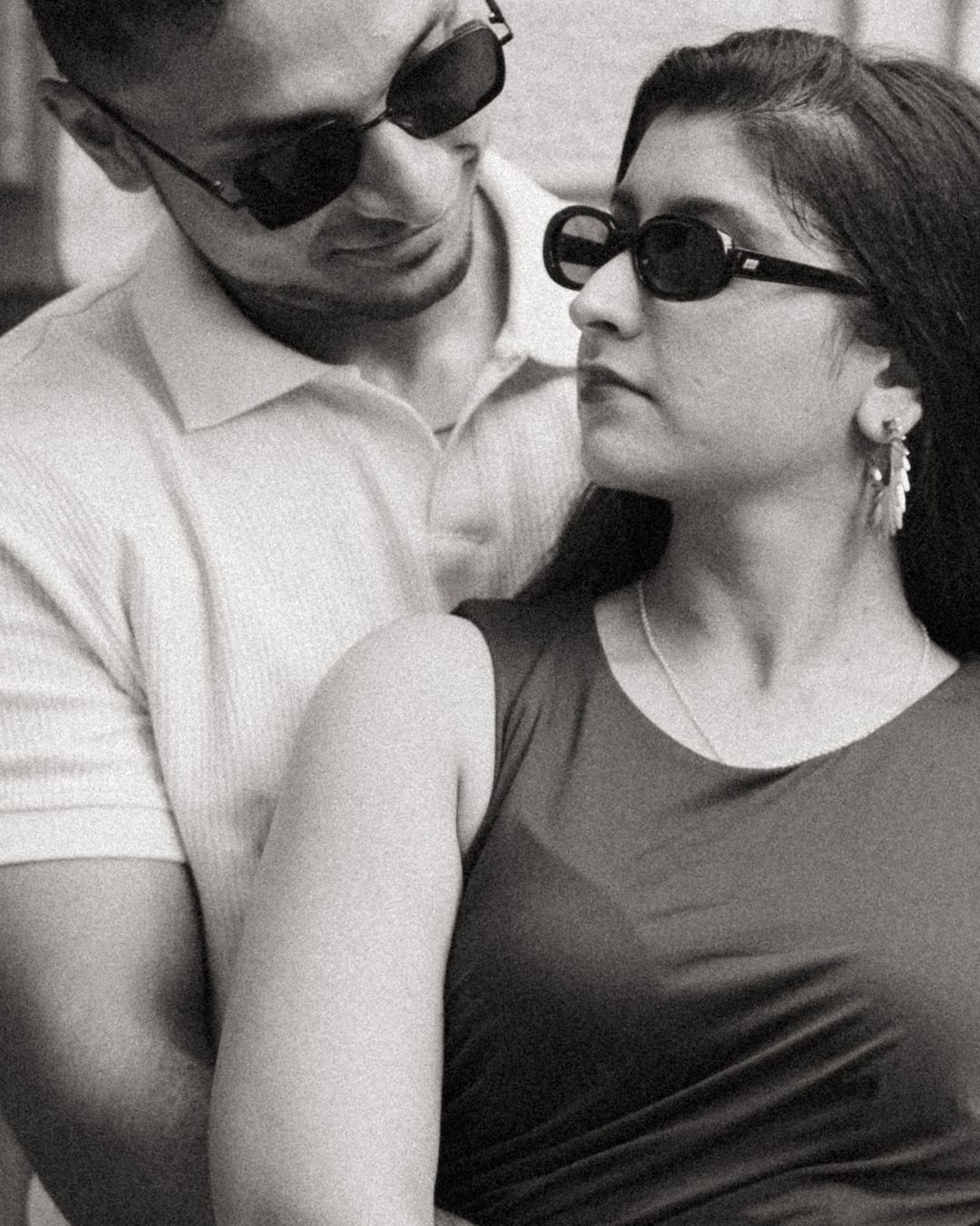 Black and white portrait of a couple in contrasting outfits sharing an intimate moment.