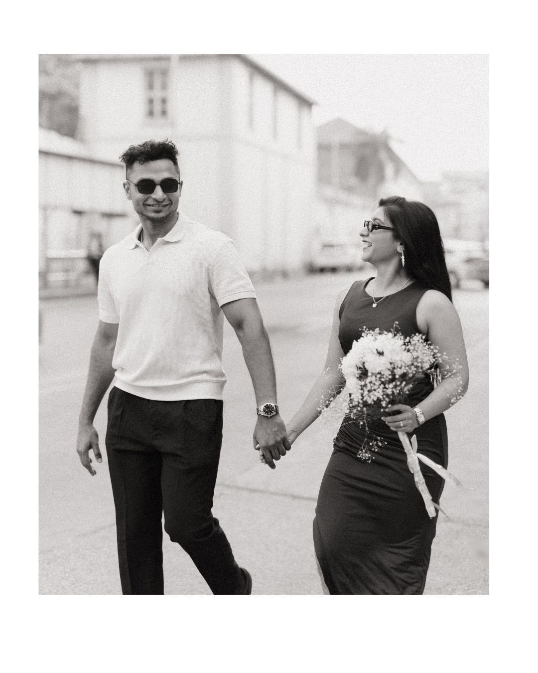 Couple walking and laughing together in casual attire during a black and white photoshoot.