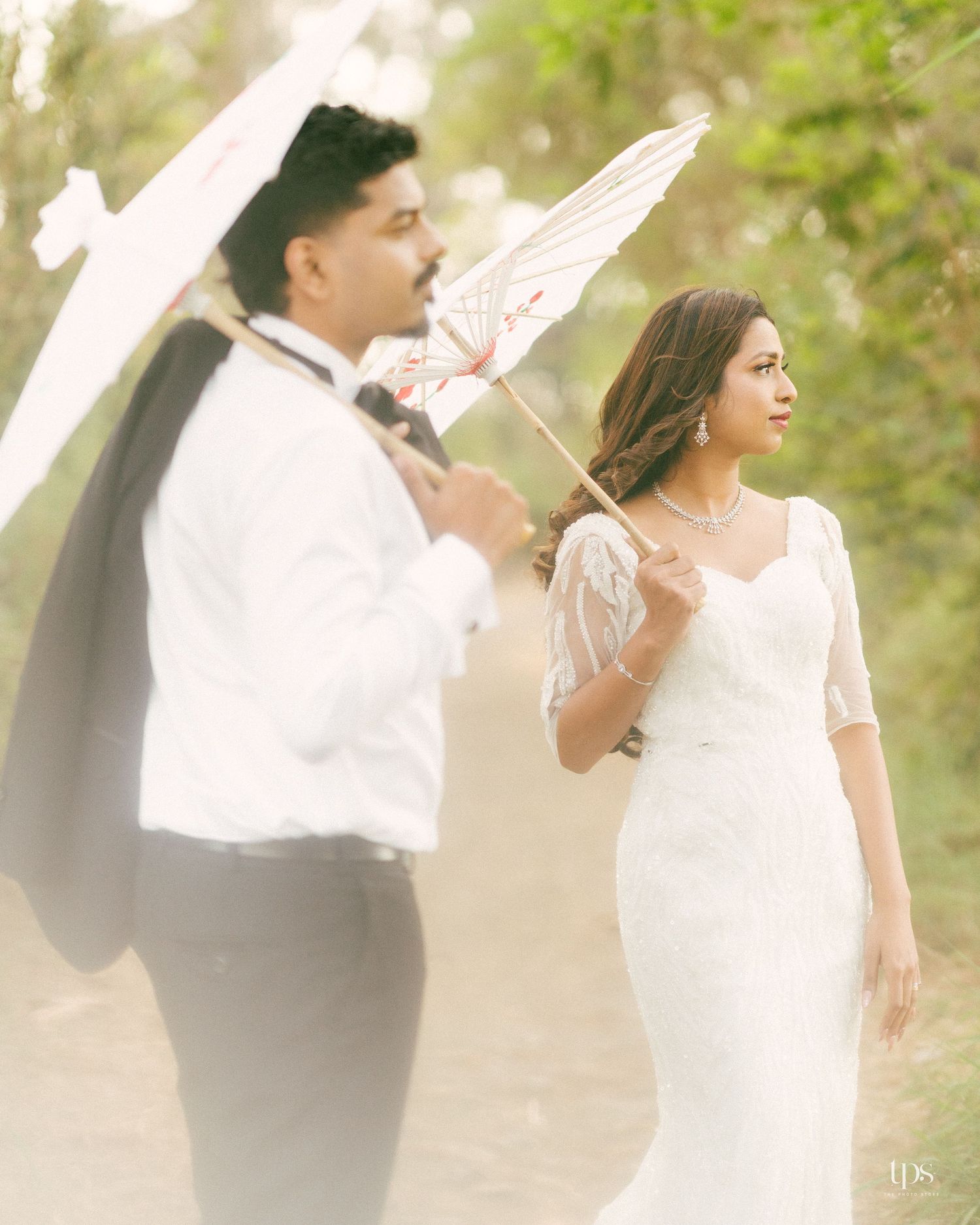 A romantic wedding photoshoot in nature featuring white parasols and elegant attire.