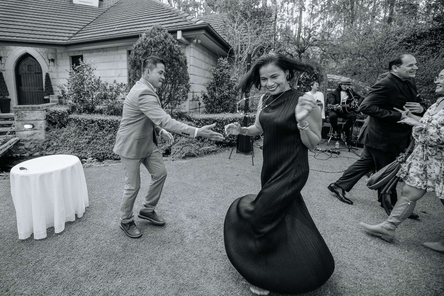 Black and white photo of wedding guests dancing energetically at reception.
