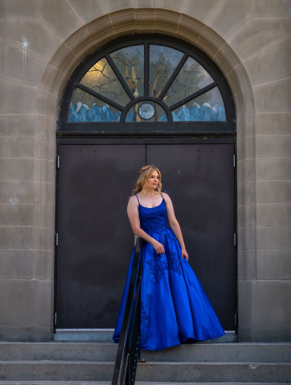 Royal blue formal gown photographed against dark arched doorway.