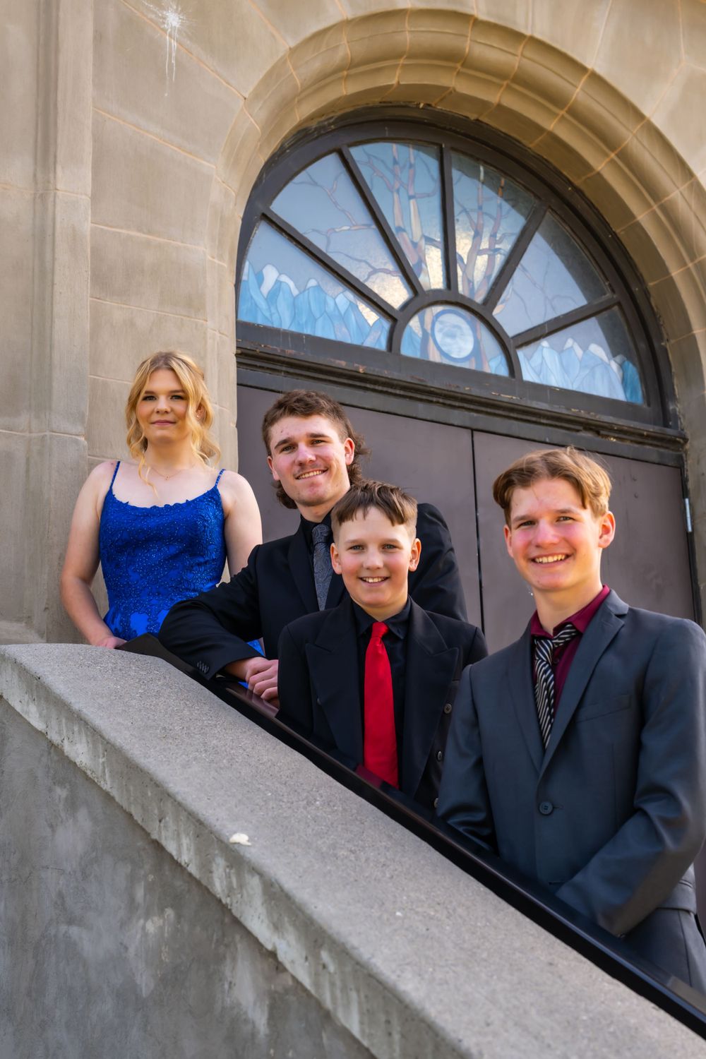 Formal group photo on stone steps under arched entrance.