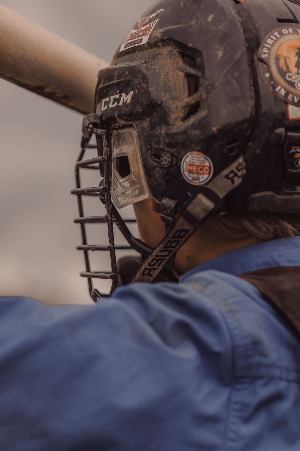 Close-up of a rodeo rider wearing a muddy CCM protective helmet at a rodeo.
