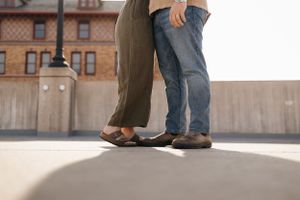 Low angle shot of two pairs of feet standing close together on urban pavement.