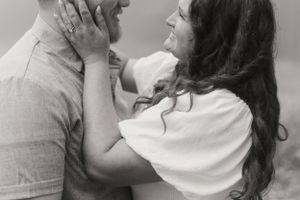 An intimate black and white portrait of a couple sharing a tender embrace.