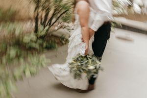 Close-up shot of a bride's dress and bouquet in motion while walking.