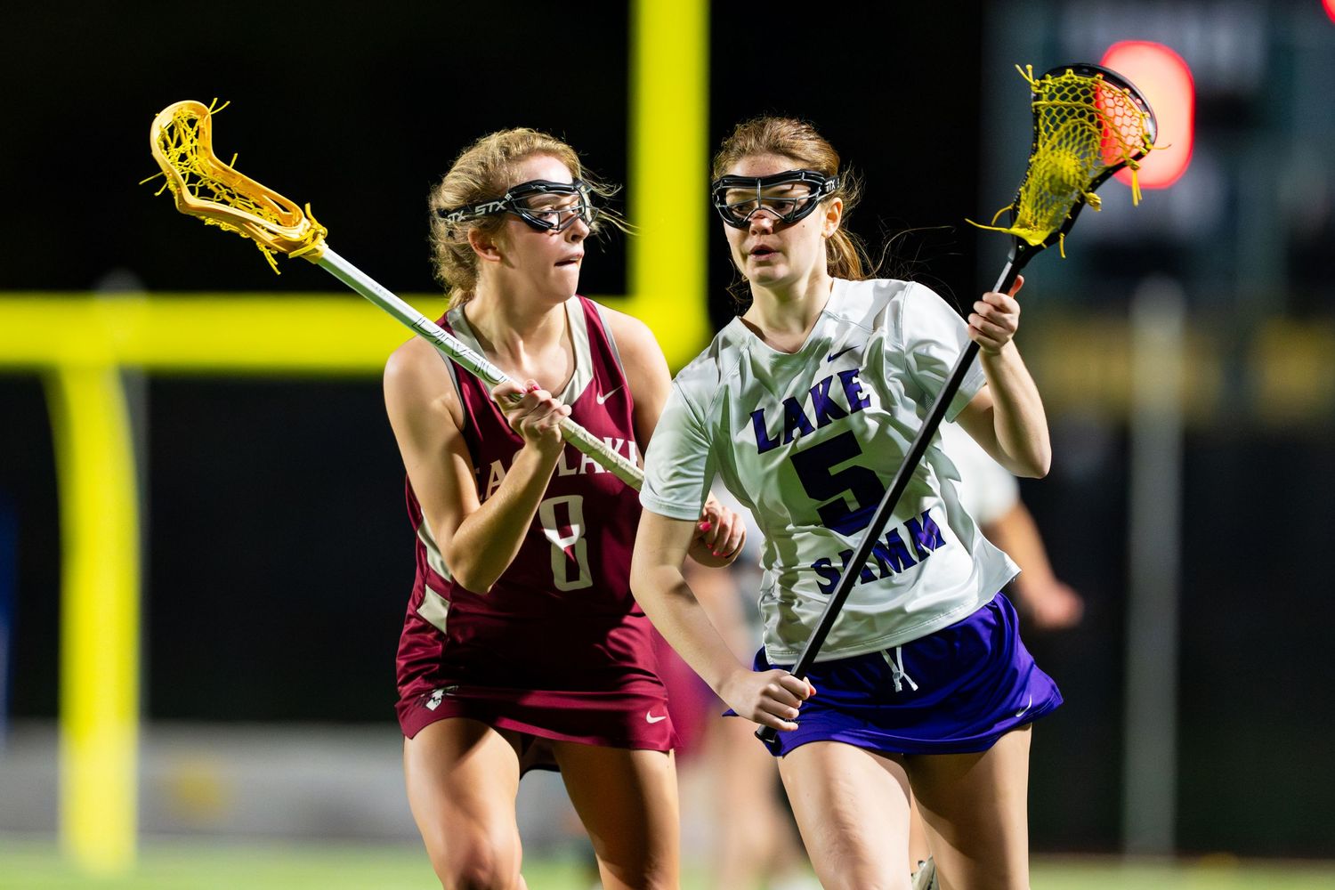 Women's lacrosse match between Lake Samm and Eastlake where two women are running side by side.