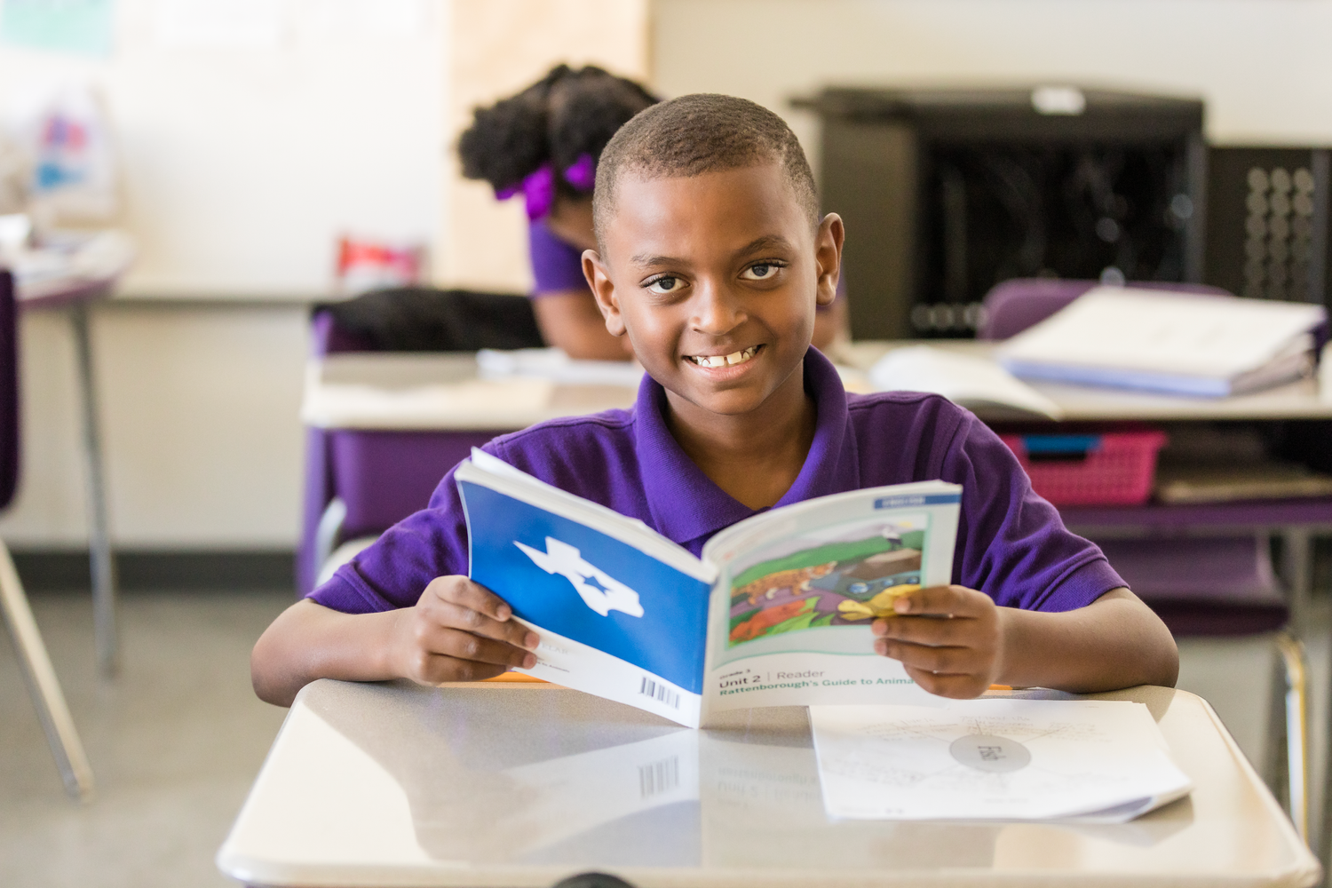 Students focused on reading books and educational materials in a classroom setting.