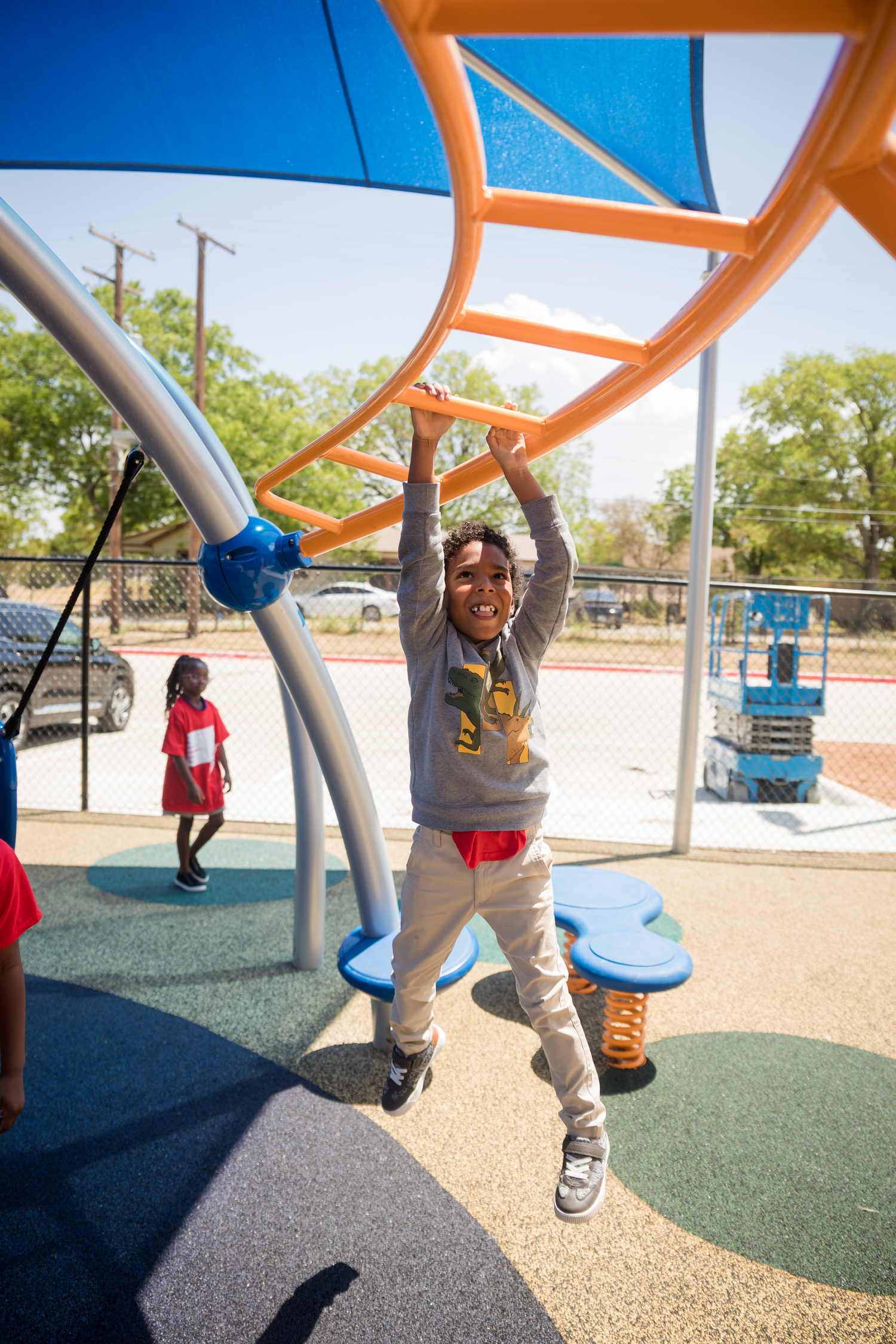 Children playing on a colorful outdoor playground structure with orange and blue elements.