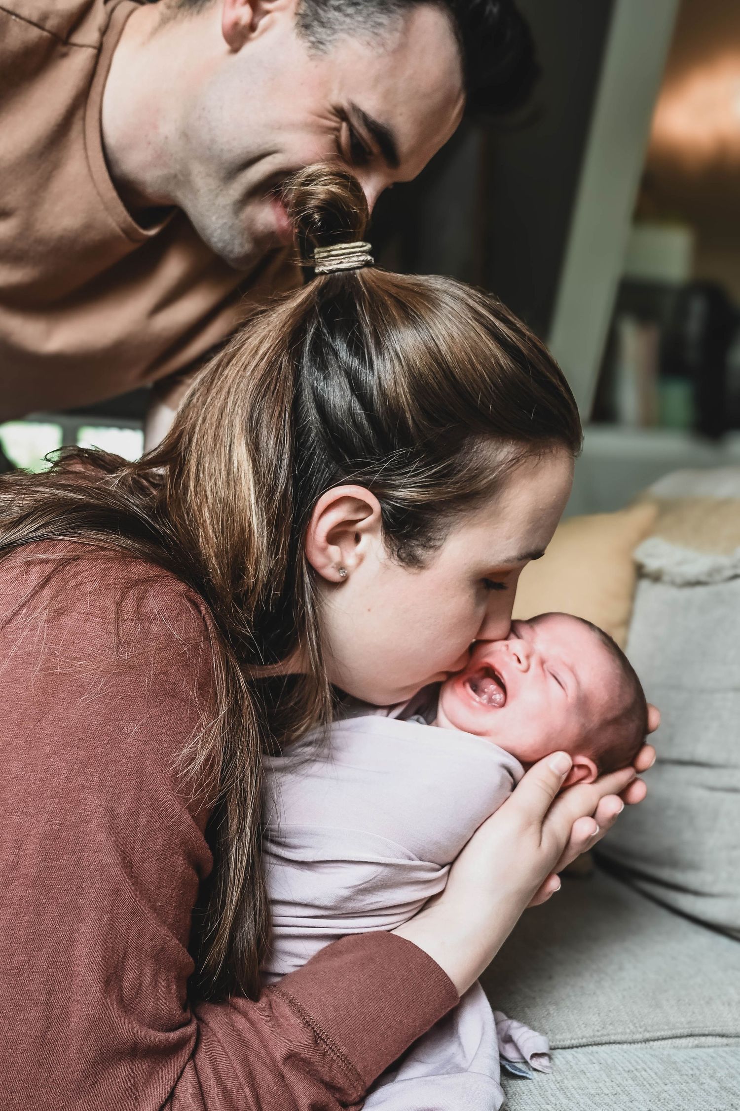 Mom kisses baby's cheeks during newborn photo shoot in Albany, NY with K. Manchuck Photography