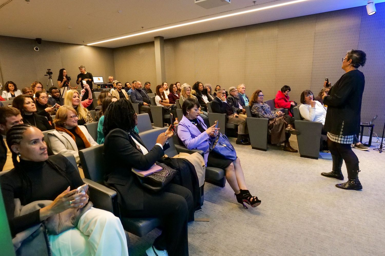 Female speaker presenting to engaged audience in modern conference auditorium during seminar.