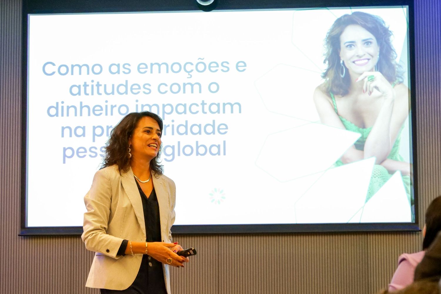 Female speaker presenting slide about emotions and money impacting global personal prosperity.