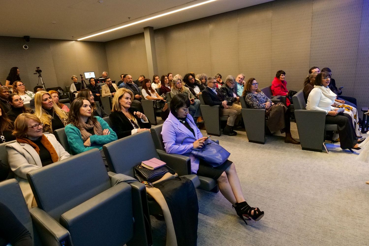 Large audience of diverse professionals attentively seated in modern conference auditorium.