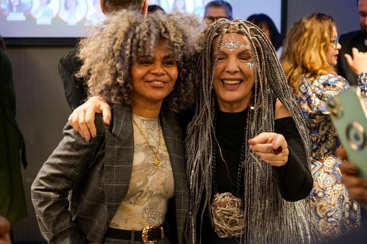 Two women smile and pose together at a vibrant professional networking event.