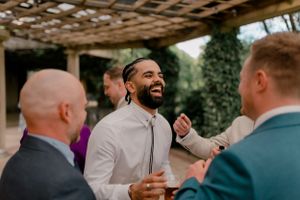 Candid moment of wedding guests laughing during outdoor reception conversation.