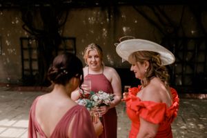 Wedding party members in pink and coral dresses sharing a candid moment during celebrations.