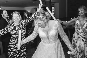 Wedding party dancing and celebrating with joy at an indoor reception with string lights.