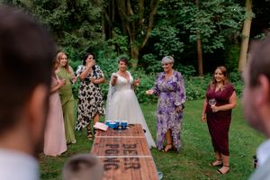 Wedding party playing a game outdoors in a garden setting with casual entertainment.